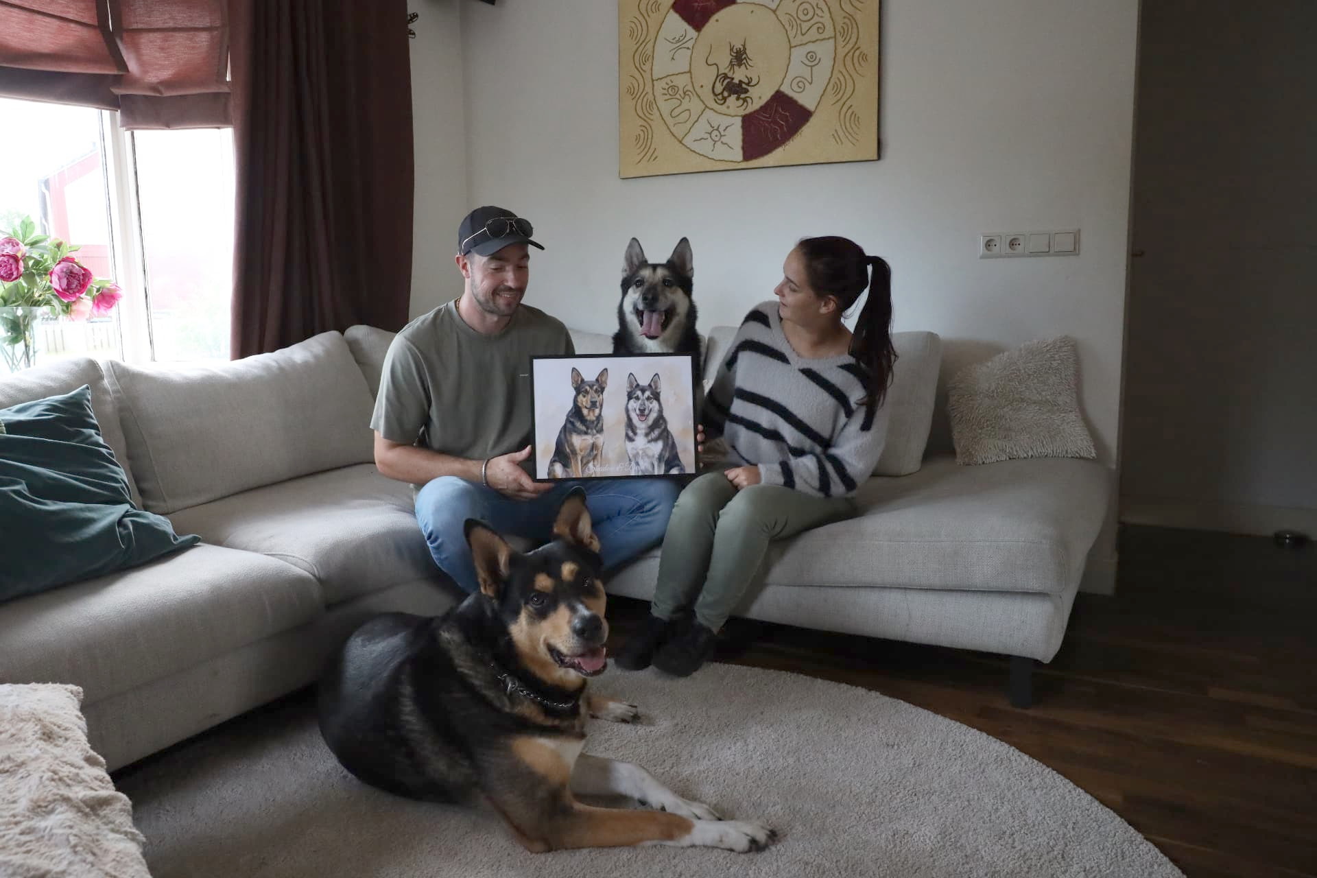 Stel thuis op de bank met hun twee honden, trots het ingelijste portret vasthoudend